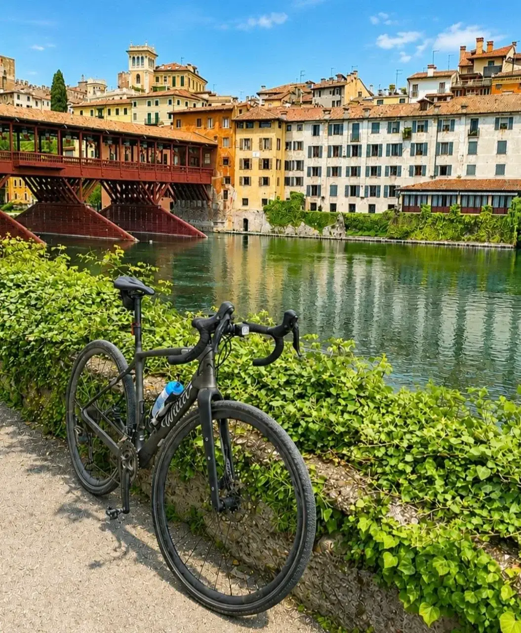 Bicicletta da corsa davanti al Ponte degli Alpini e alle case sul Brenta a Bassano del Grappa