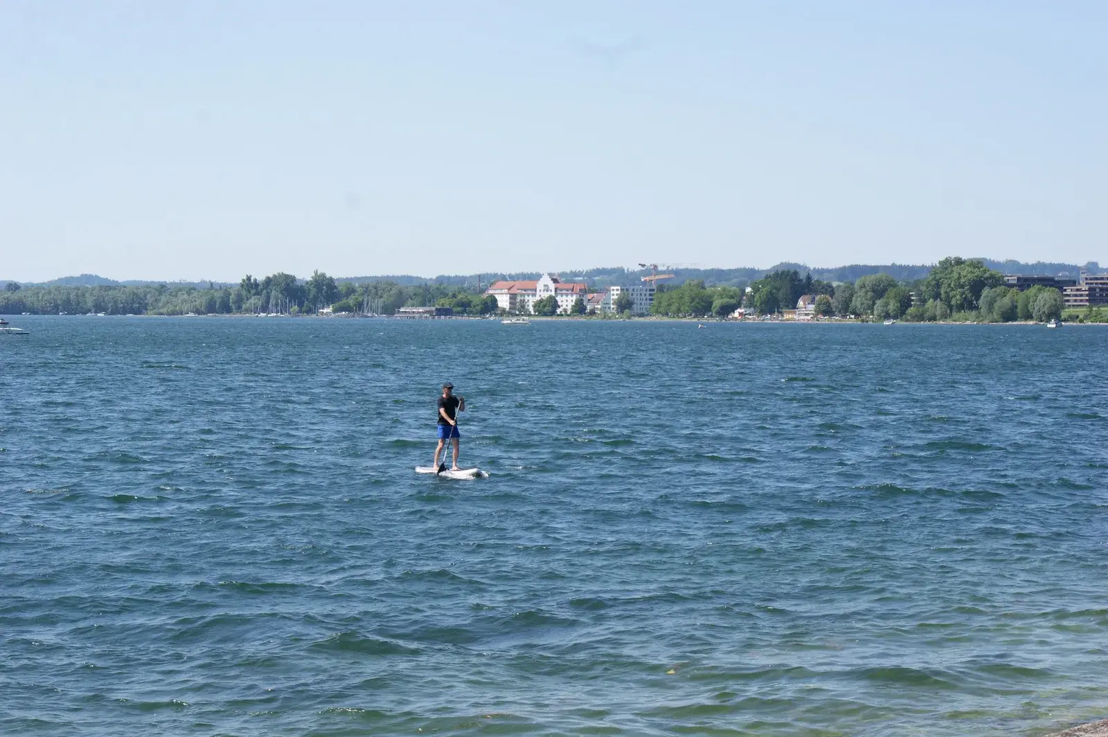 Una persona pagaia in stand up paddle su un lago increspato dal vento