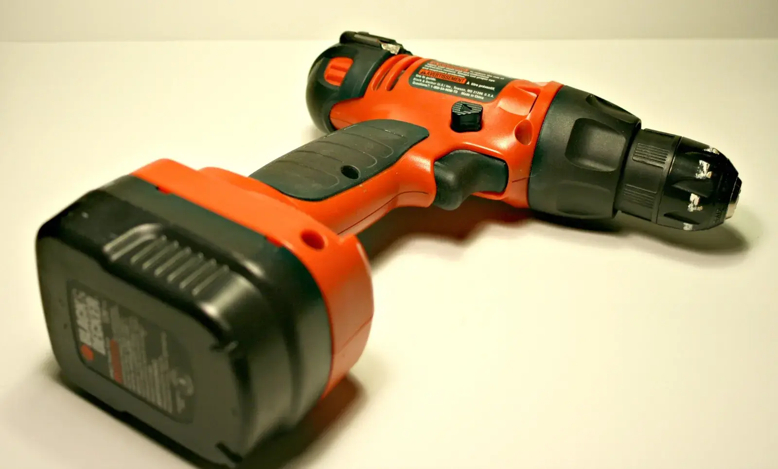 Un trapano avvitatore a batteria arancione su un fondo chiaro