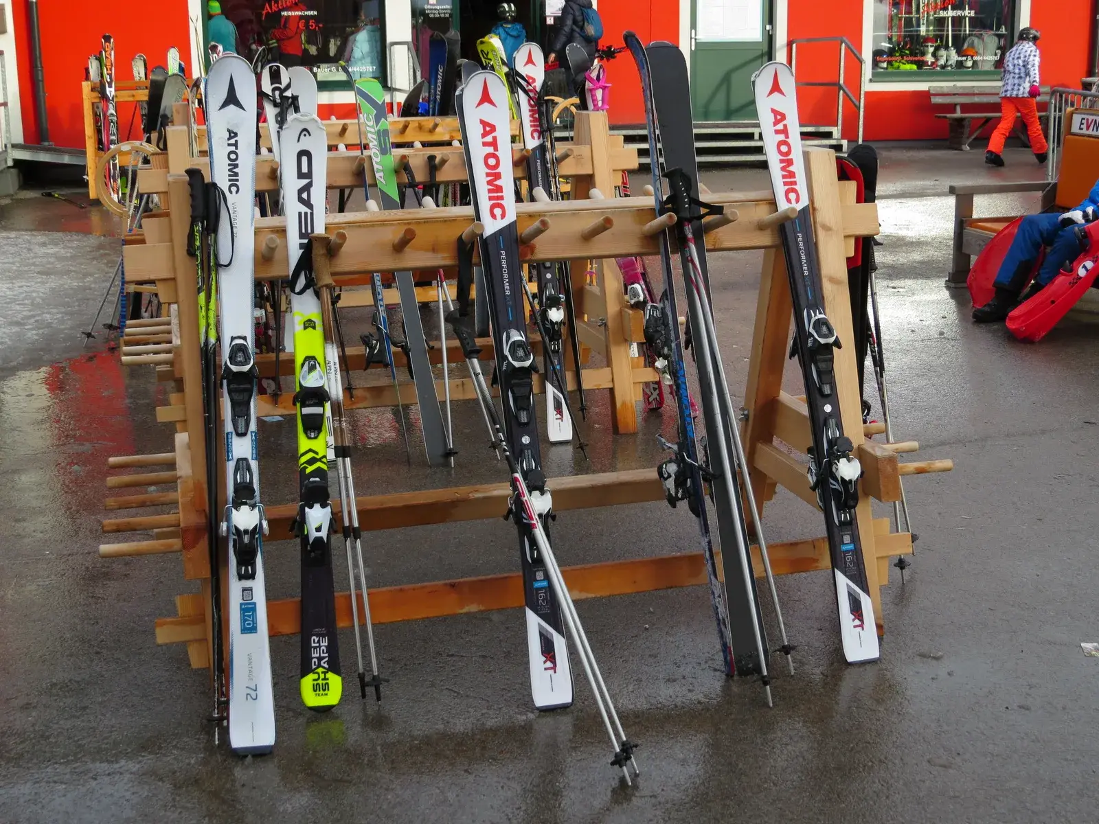 Sci alpini appoggiati a una rastrelliera di legno in una località sciistica