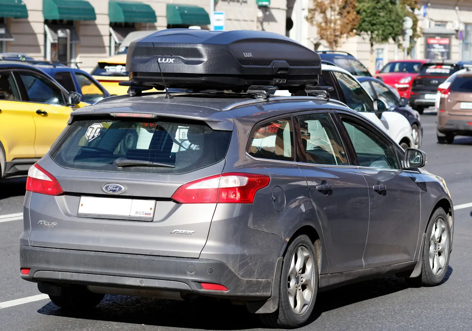 Station wagon con un box portatutto nero sulle barre del tetto