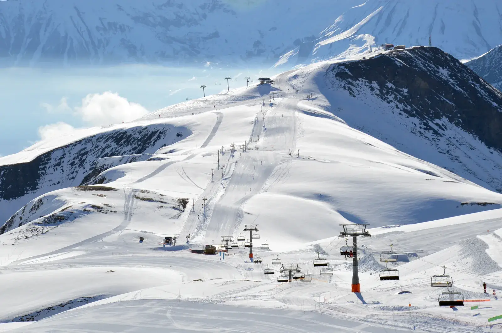 Piste da sci e impianti di risalita su un crinale innevato sotto il cielo azzurro