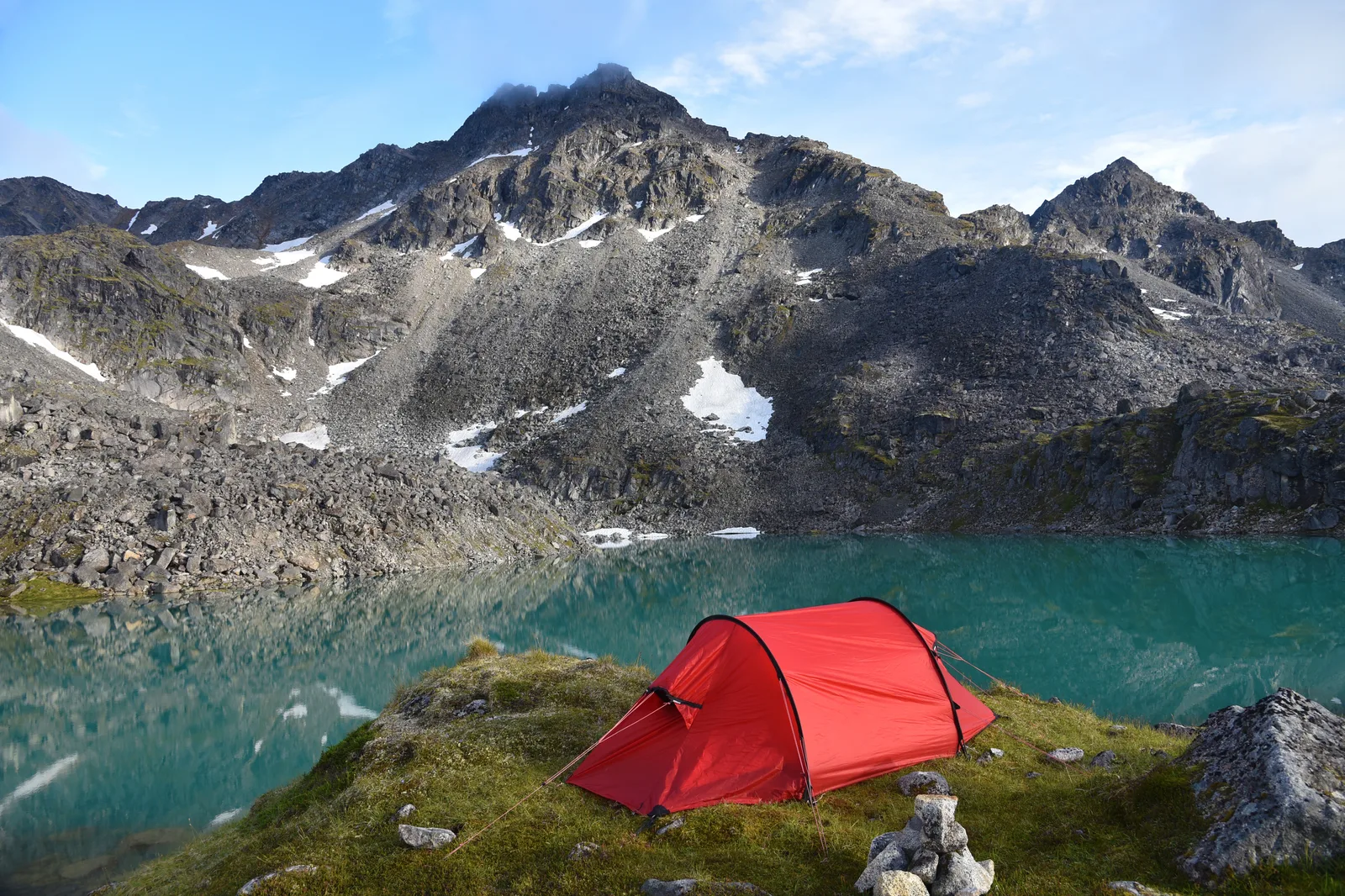 Una tenda da campeggio montata su un prato in montagna vicino a un lago