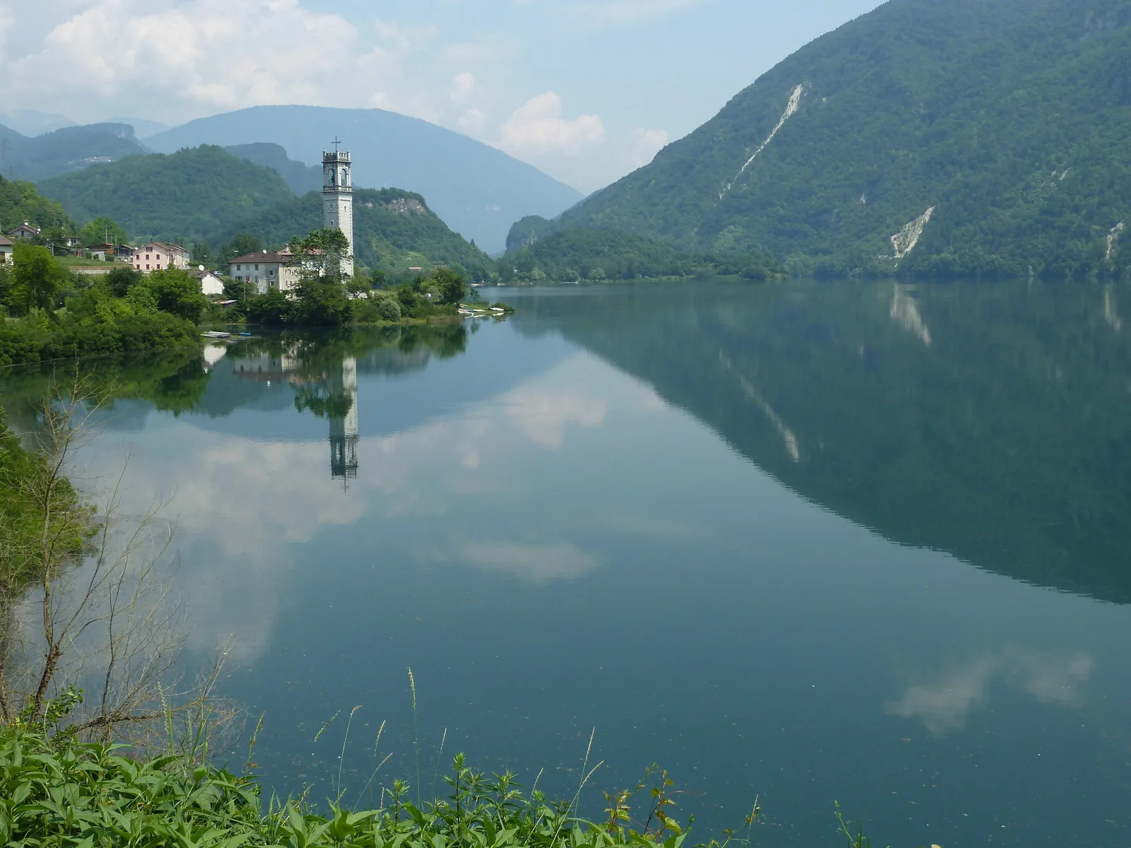 Il borgo di Rocca di Arsiè riflesso nell’acqua ferma del Lago di Corlo