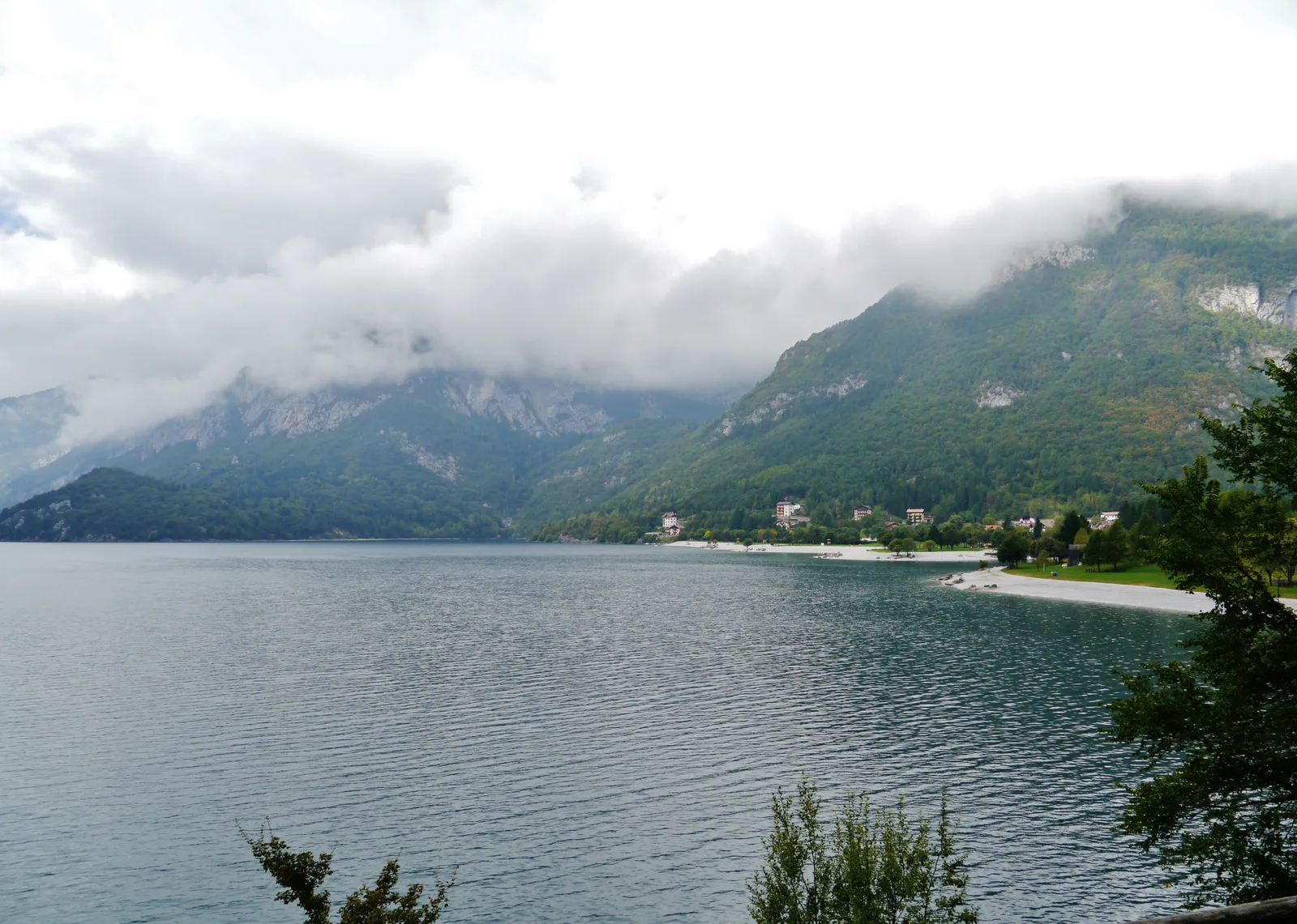 La riva del Lago di Molveno con acqua trasparente e sponde di ghiaia