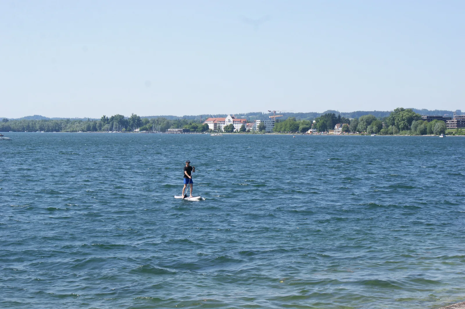 Una persona pagaia in stand up paddle su un lago increspato dal vento