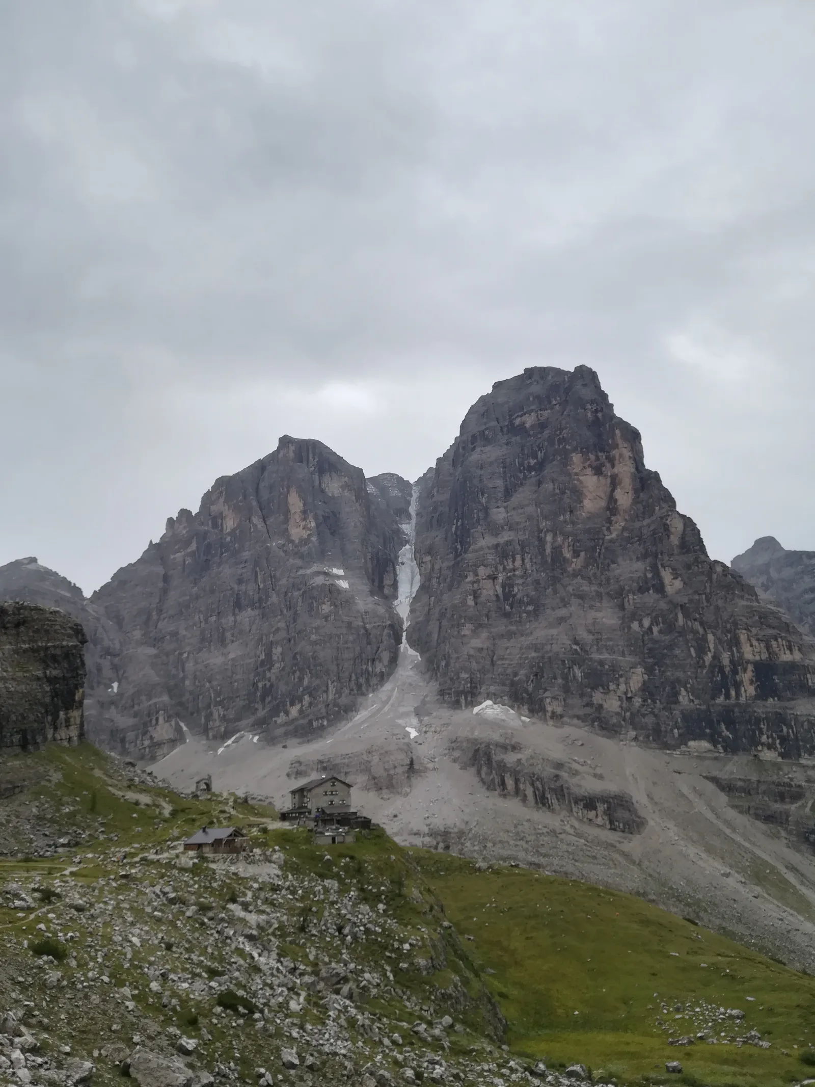 Il Rifugio Brentei visto dal sentiero, con le pareti del Brenta alle spalle