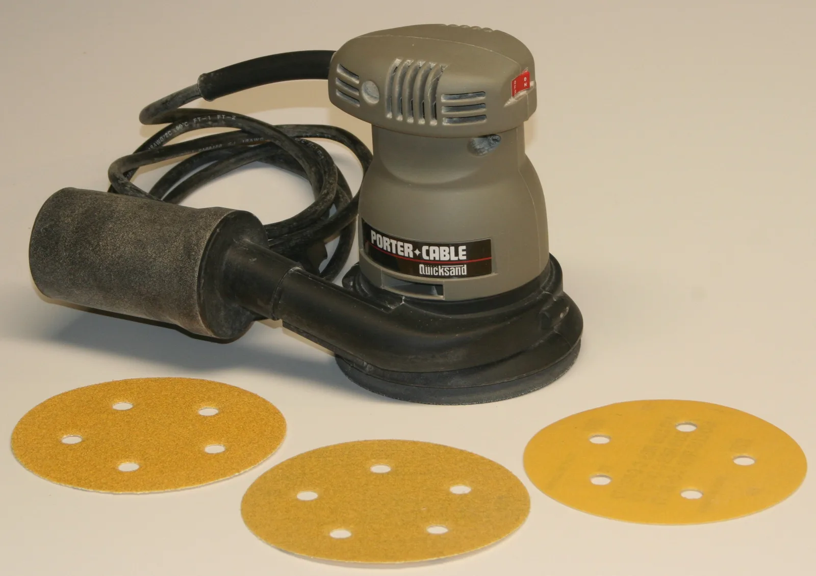 Una levigatrice rotorbitale elettrica appoggiata su una superficie di legno