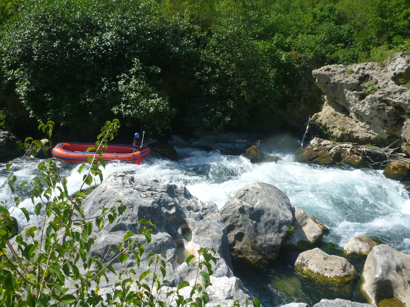 Un gruppo scende un fiume in gommone da rafting con casco e giubbotto